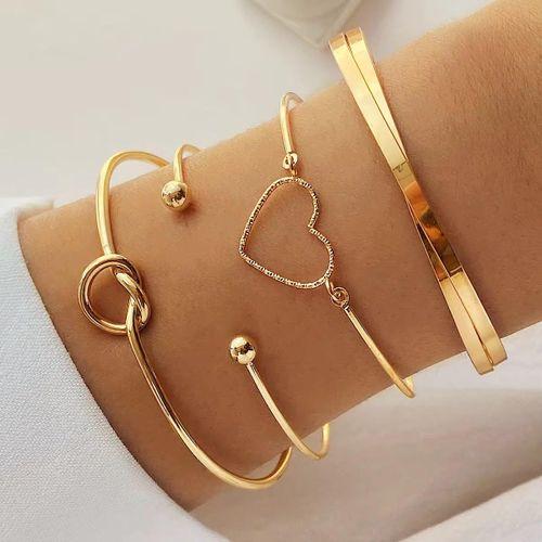 Un ensemble de quatre bracelets dorés, majoritairement de type jonc